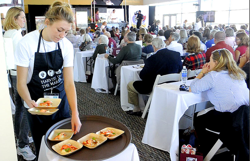 Servers at Thursday’s Maine Lobster Chef of the Year competition deliver samples of the dishes being made by the contestants to the audience for judging at the annual Harvest on the Harbor event.