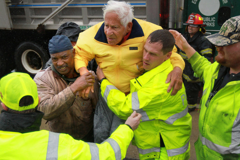 An elderly man is taken to safety by volunteer firefighters in West Atlantic City, N.J., on Monday.