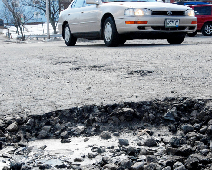 In this 2008 file photo, a vehicle makes its way past a pothole on a section of Chestnut St. in Portland. A new report says Mainers on average pay an extra $300 because of poor road conditions, and it's even worse around Portland.