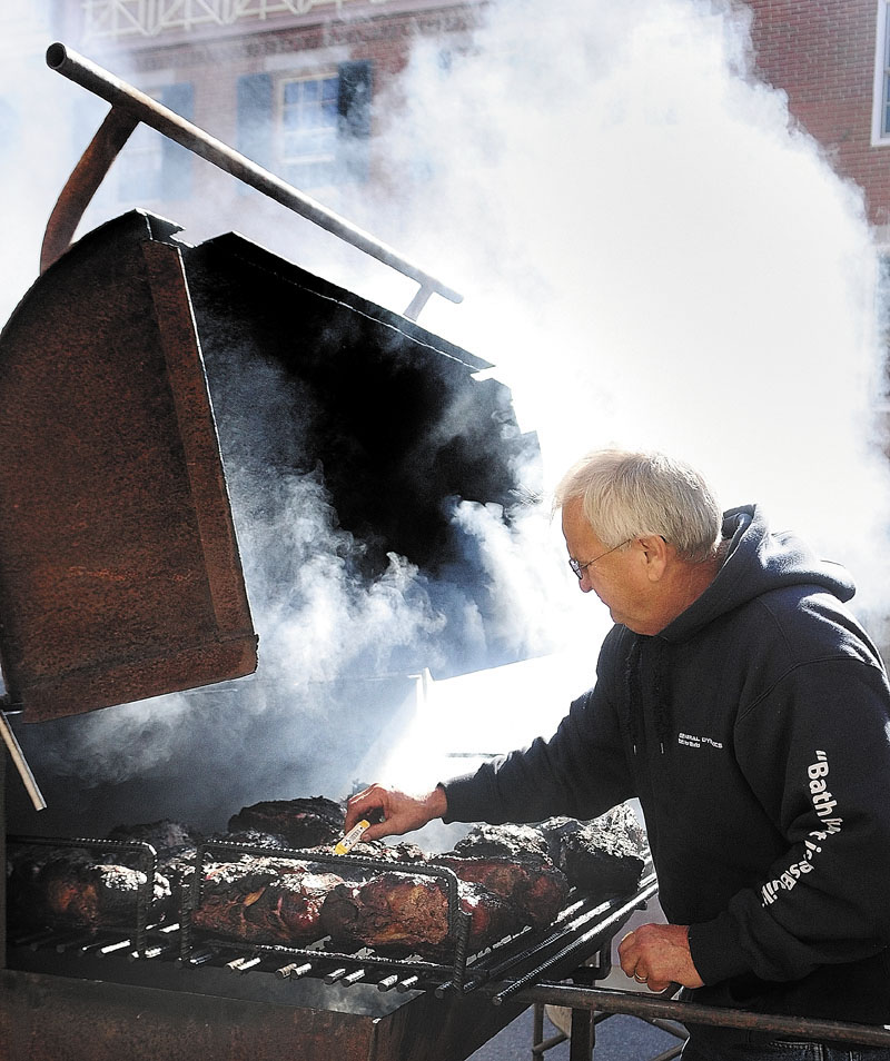 Bob Lutz is shrouded in smoke as he checks the temperature of a Boston Butt he's cooking in front of Gerard's Pizza during the Swine and Stein event on Saturday morning in downtown Gardiner. Lutz said that he would pull the meat when it was at 190 degrees, which should be cooked up moist and falling apart for pulled pork sandwiches. He'd lit the fire at 4:30 a.m. and was cooking the meat at low temperatures for several hours.