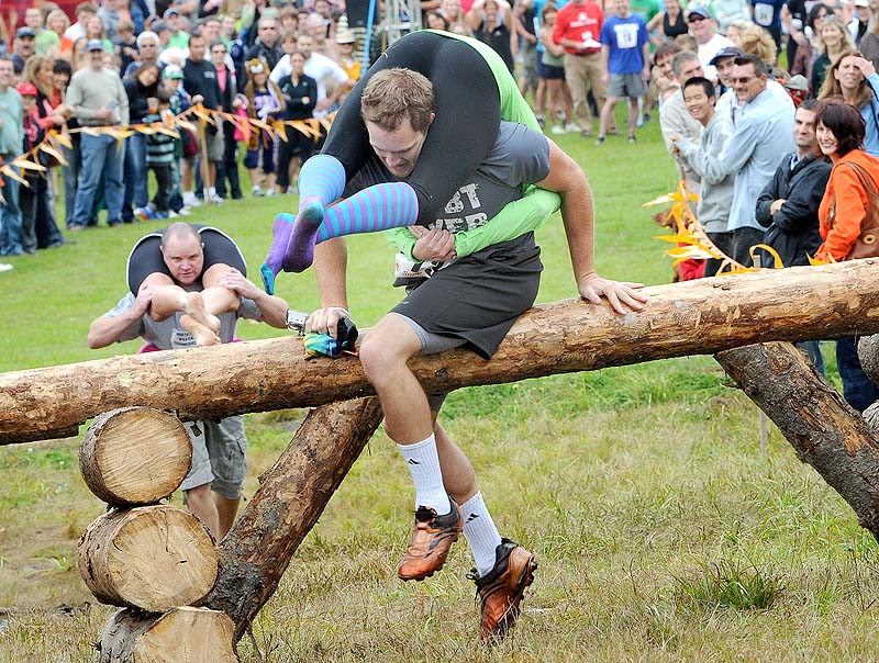 Brendan Doherty and Lauren McMillan from Brookline, Mass., lead Jim and Tanya Watson from South Portland over the first obstacle during the 13th annual North American Wife-Carrying Championship at Sunday River in Newry on Saturday.
