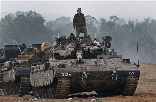 An Israeli soldier stands on a tank at a staging area near the Israel Gaza Strip Border, southern Israel, early Tuesday.