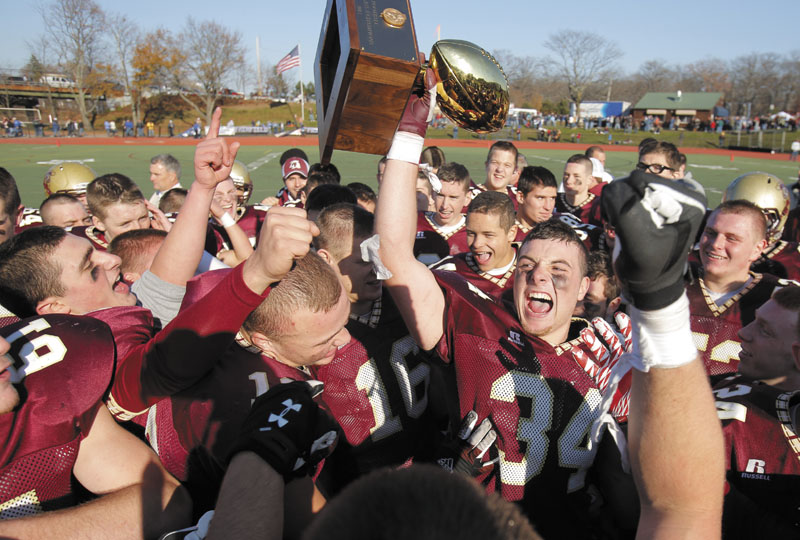 Senior Nick Kenney of Thornton Academy hoists the championship trophy after the Trojans defeated Lawrence, 37-23, to win the Class A state football championship on Saturday at Fitzpatrick Stadium in Portland.