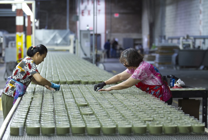 In this Aug. 30, 2012 file photo, production line workers, Xiao Yins-Wong, left, and Chui M. Wong, straighten the wick in the candles at Chesapeake Bay Candle factory in Glen Burnie Md. The U.S. economy grew at a 2.7 percent annual rate from July through September, much faster than first thought. The strength is expected to fade in the final months of the year because of uncertainty about looming tax increases and government spending cuts. (AP Photo/Jose Luis Magana, File)