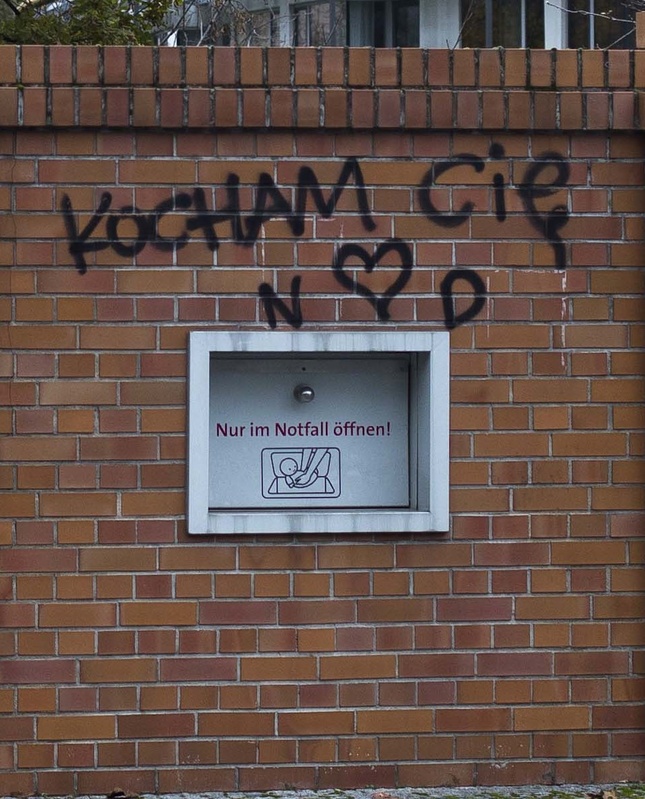 A "baby box" is fixed in a wall near a hospital in Berlin. The text on the door reads "Only open in emergency." Graffiti on the wall reads "I love you" in Polish.