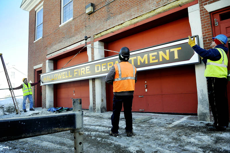 Workers hang a sign on the exterior of the Hallowell Fire Department station on Second Street in February 2011.
