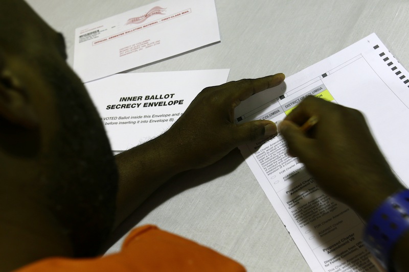 In this photo taken Oct. 24, 2012 , a prisoner votes at the D.C. Jail in Washington. The voters at this southeast Washington polling place were all dressed alike: orange jumpsuit, white shoes. And when they finished voting they went back to their cell block, not back to work. Still, voting inside the D.C. Jail looked a lot like voting at precincts around the country.(AP Photo/Jacquelyn Martin)