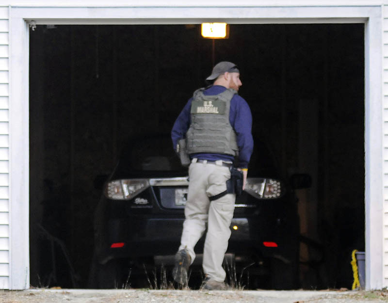 A U.S. Marshals Service investigator searches the garage at the residence of Barbara Cameron, the ex-wife of fugitive James Cameron, Tuesday in Hallowell. Authorities are continuing to hunt for Maine’s former top drug prosecutor.