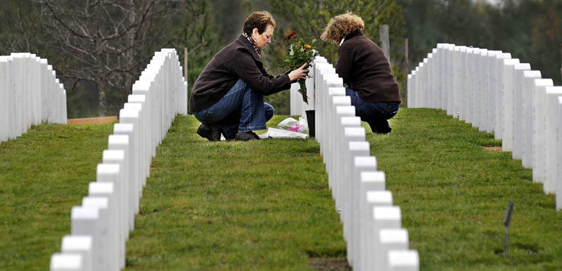 Lisa Crowell, left, lays flowers Sunday on the headstone of her husband, Wayne, with her sister-in-law, Sheila Crowell, at the Maine Veterans' Memorial Cemetery in Augusta. Wayne C. Crowell, of Wayne, who died in May, received two Purple Hearts while serving with the Army in Vietnam.