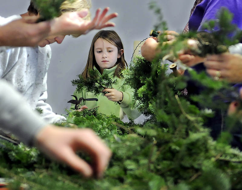Many hands wrap and clip boughs Sunday at the Windsor Historical Society, during the annual wreath-making event. Andrea Richardson, 8, of Windsor, is one of several who volunteered to make the holiday decorations to adorn the houses and barns at the Society.