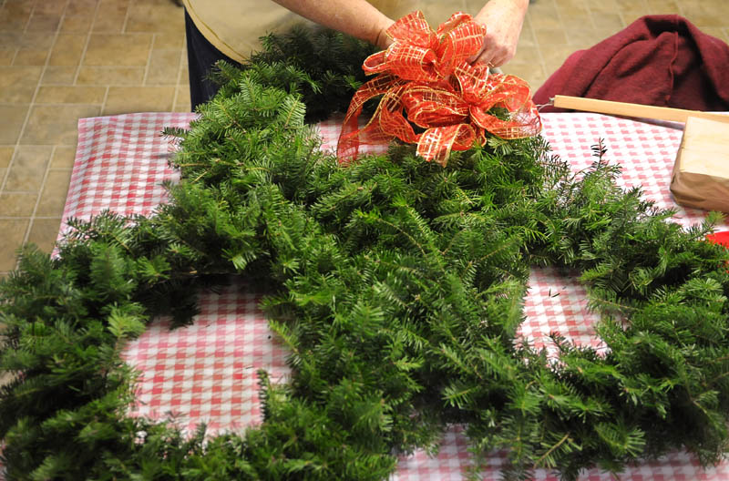 Priscilla Brann wraps bows around wreathes created at the Windsor Historical Society on Sunday.