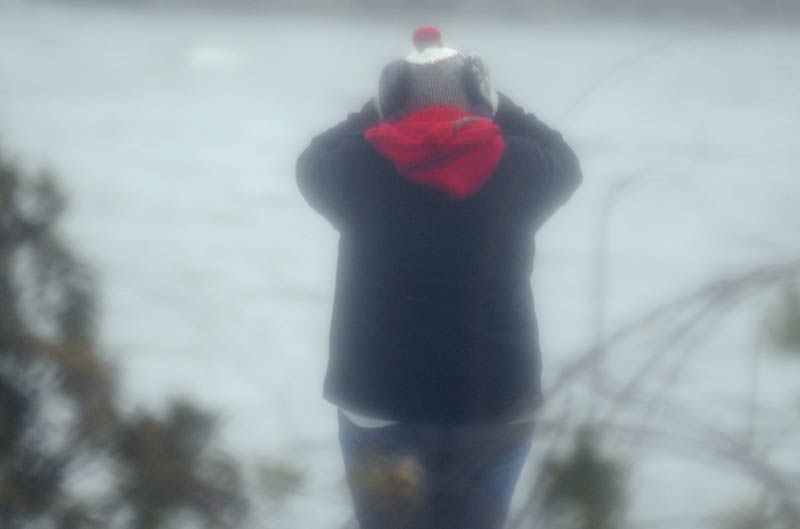 Shannon Bubier covers her eyes Thursday while observing waves on Maranacook Lake in Winthrop. Gusts of wind up to 30 mph buffeted people across Maine as a nor'easter washed across the state. A self-described "weather nut," Bubier said the temperature was "freezing" in the gusts coming across the lake.