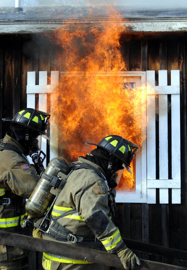 Firefighters walk past a burning window Sunday during a controlled burn of a donated home and barn at the Kelley Bros. Farm in Pittston. Dozens of firefighters from communities in Lincoln and Kennebec County practiced extinguishing blazes and rescuing trapped people during the exercise, Pittston Fire Chief Jason Farris said.