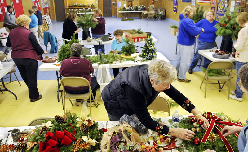 Volunteers assemble evergreen floral centerpieces, decorate boxwood trees and wrap wreaths Thursday at the Manchester Lions Club. More than 50 people from a variety of community groups are assembling the holiday floral designs to be auctioned off Sunday at Manchester's annual fuel assistance fundraiser at the elementary school. The 2 p.m. auction will be followed a tree lighting ceremony. All proceeds will be donated to winter heating fund for Manchester residents.