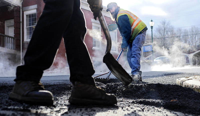 Ferraiolo Construction Co. workers Mark Megill, right, and Dave Buzzell spread pavement Monday on Church Street in Gardiner. The road received a new layer ahead of winter, as temperatures hovered below freezing.