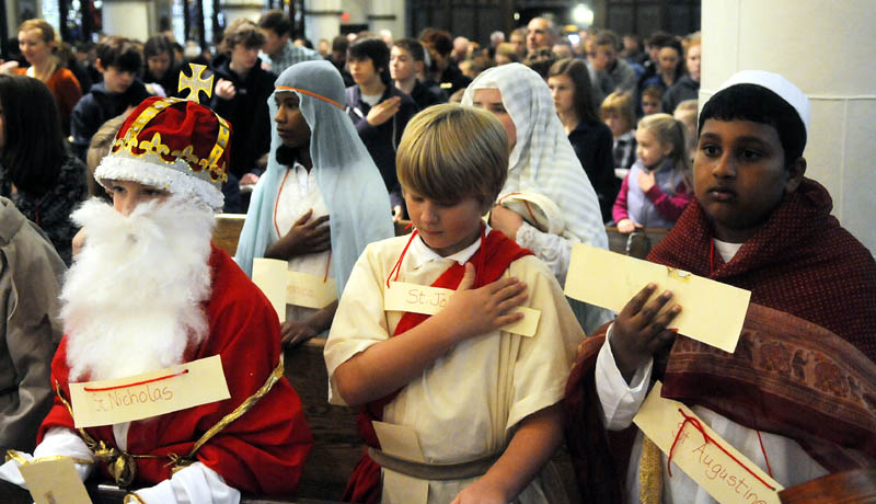 St. Michael School fifth graders bless themselves during a service Thursday at St. Mary's Church in Augusta on All Saints Day. Children from the private school dressed as saints during the annual Mass to celebrate individuals canonized by the Catholic Church.