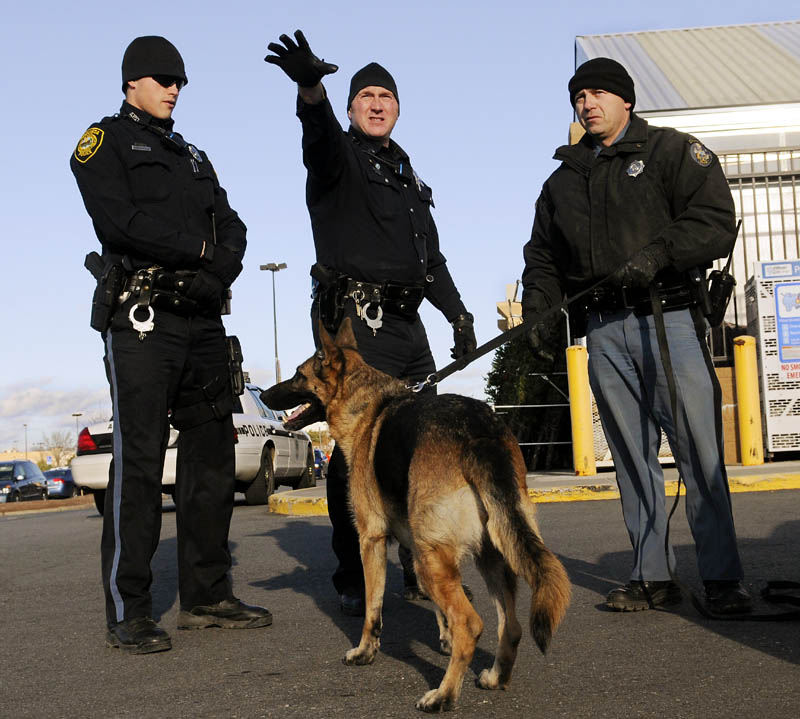 Augusta Police officer Niko Hample, left, and Sgt. Daniel Boivin, center, confer with State Trooper Rick Moody as they prepare to track a man who robbed the pharmacy of the Walmart in Augusta on Monday. Police followed a tracking dog who picked up the scent of the robber, who fled with drugs toward Civic Center Drive.
