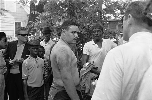 In this June 14, 1963, photo, Lawrence Guyot, 23, removes his shirt in Jackson, Miss., to show newsmen where he says Greenwood and Winona police beat him with leather slapsticks.