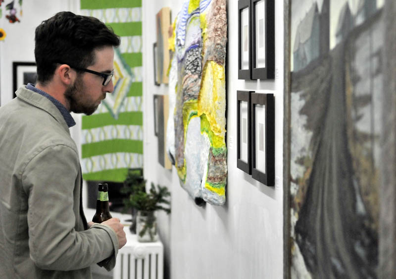 Zach Vickers, of Coopers Mills, looks at art work at Common Street Arts in Waterville during the opening of a new exhibit, featuring a collection of art inspired by local farms over the last growing season, on Saturday.