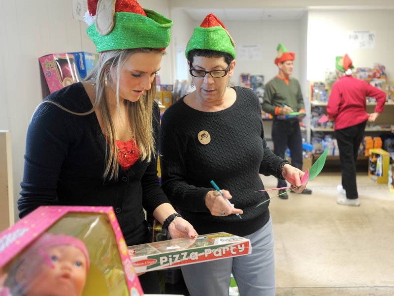 Kasie Flowers, left, and Tina Carter, right, of the Waterville Housing Authority, pick a toy from the shelf to pack inside a gift box, to be distributed to disadvantaged children in the area for the holidays, at the Maine Children's Home for Little Wanderers in Waterville Thursday.