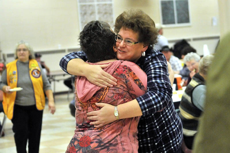 Jill Dart, right facing, hugs volunteer Shelli Mellows, after her meal at the 23rd annual community Thanksgiving Day dinner at Messalonskee High School in Oakland, on Thursday. Dart's husband recently died, and she attended the community dinner to surround herself with friendly smiles and a hot meal for the holiday.