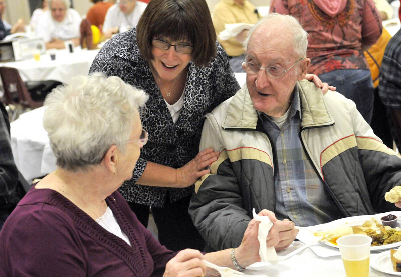 Volunteer Patsy Belanger, center, takes a moment to say hello to Sadie and Charlie Sturtevant, at the 23rd annual community Thanksgiving Day dinner at Messalonskee High School in Oakland, on Thursday.