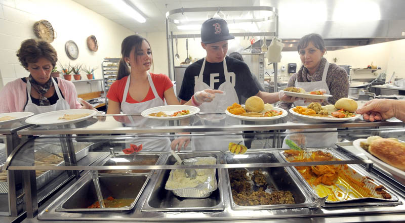 Volunteers, from left to right, Donna Russon, Alyssa Smith, 16, Ethan Foss, 18, and Sarah Harding, 30, serve up turkey and all the fixings at the 23rd annual community Thanksgiving Day dinner at Messalonskee High School in Oakland, on Thursday.