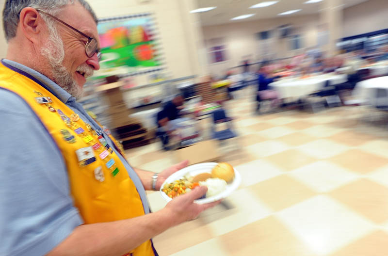 Oakland Lions club member and volunteer Bill Farnham delivers a plate of turkey to a table at the 23rd annual community Thanksgiving Day dinner at Messalonskee High School in Oakland, on Thursday.