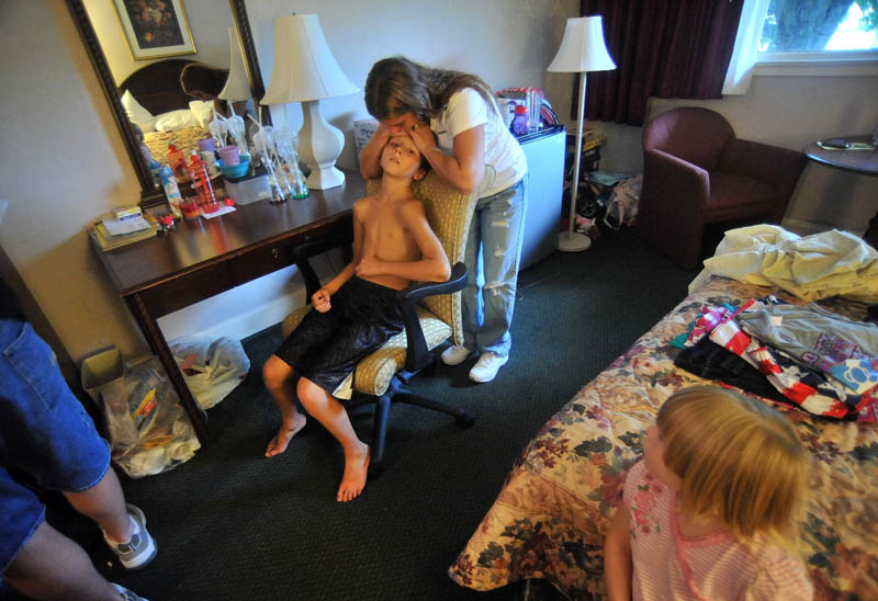 Janet White comforts her son, Dakota LaBrie, 11, in the hotel room that has been serving as home. The Whites had very little money at the time of the fire that destroyed their home, so extended periods of time in a hotel has been very costly.