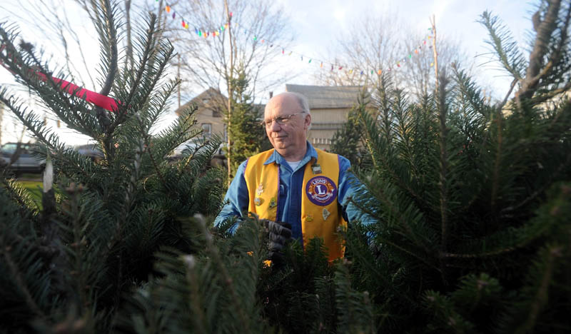 Ray Watson, 68, of Oakland, and a member of the Oakland Lions Club, arranges Christmas trees for sale on Kennedy Memorial Drive in Oakland. Proceeds help purchase warm clothes and toys for disadvantaged children in the area.