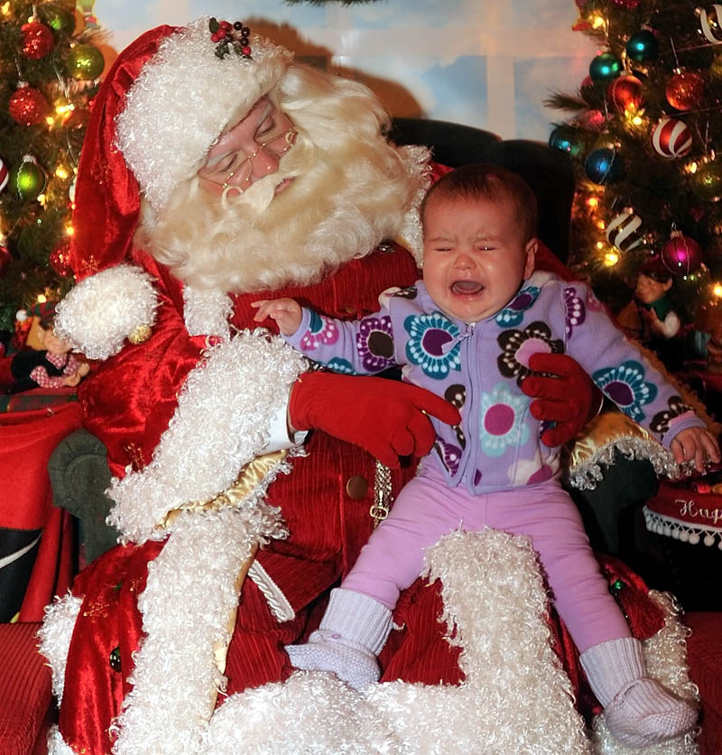 Avery Rodrigue, 7 months, of Saritoga, N.Y., cries as he sits on Santa Claus's lap at Kringleville, in Castonguay Square in downtown Waterville, on Saturday.
