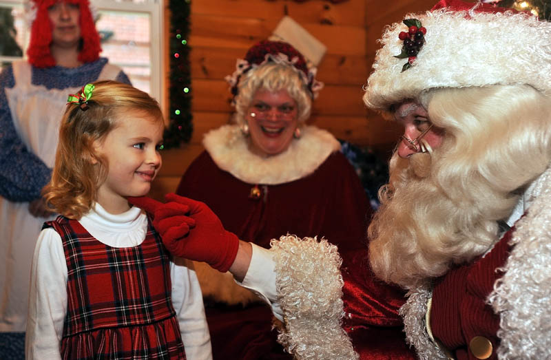 Hannah Rauch, 3, smiles as Santa Claus says hello, at Kringleville in Castonguay Square in downtown Waterville, on Saturday.