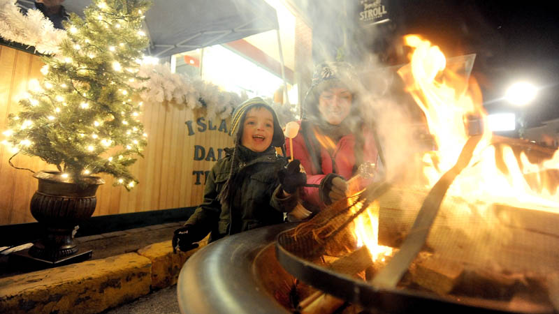 Christina Easler, right, and her son, Gavyn, 4, enjoy a hot marshmallow over an open fire on Water Street, at the Holiday Stroll parade on Water Street in downtown Skowhegan, on Friday.