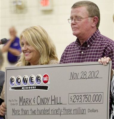 Cindy and Mark Hill hold a celebratory check for having one of the two winning Powerball tickets in Dearborn, Mo., on Friday.