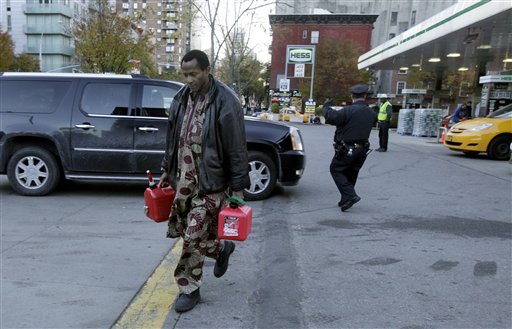 A man carries two filled gas cans at a gasoline station in New York on Friday. Gas is available to drivers with license-plate numbers ending in an odd number or a letter on Friday. On Saturday, drivers with license plates that end in even numbers or zero can fuel up.