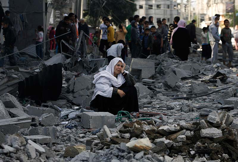A Palestinian woman sits in rubble following an Israeli airstrike in Rafah refugee camp in southern Gaza Strip on Sunday. An Israeli envoy held talks with Egyptian officials Sunday on a ceasefire in his country's offensive on Gaza as Israel widened the range of its targets, striking more than a dozen homes of Hamas militants and two media officials.