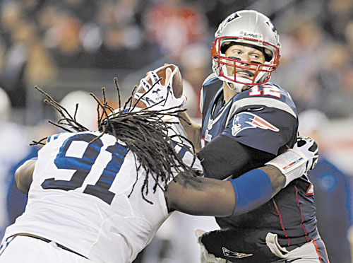 HERE IT COMES: New England Patriots quarterback Tom Brad, right, eludes Indianapolis Colts defensive end Ricardo Mathews (91) to get a pass off during the second quarter Sunday at Gillette Stadium in Foxborough, Mass.