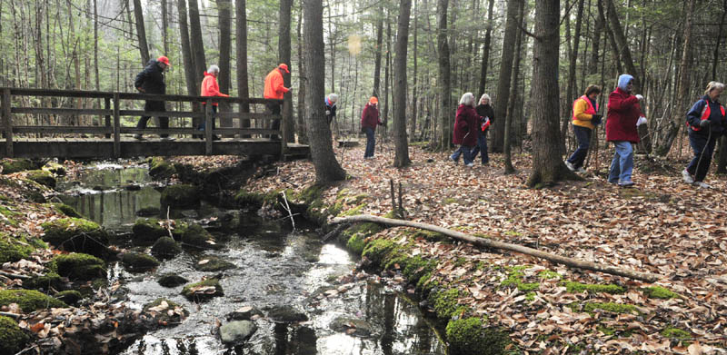 Hikers cross a bridge on Friday morning at the Fogg Conservation Area in Readfield.