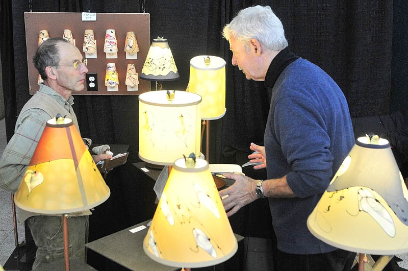 Customer Kyrill Schabert, of Jefferson, left, chats artist Stuart Loten about his lamps and shades on Saturday afternoon during 16th Annual Crafts at the Museum Show in Augusta. The Maine State Museum is located off of State Street just south of the State House and show continues today from 10 a.m.to 4 p.m.