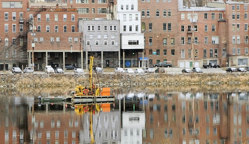 Workers drill from a barge on Tuesday afternoon in the middle of the Kennebec River, in downtown Augusta.