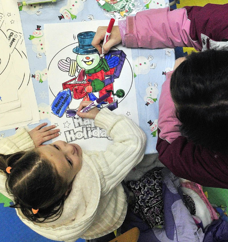 Jenna Jensen, 4, and her mother, Natasha Jensen, both of Portland, work on coloring a picture in a craft room that was part of the annual tree lighting events on Saturday, on Water Street in downtown Augusta.
