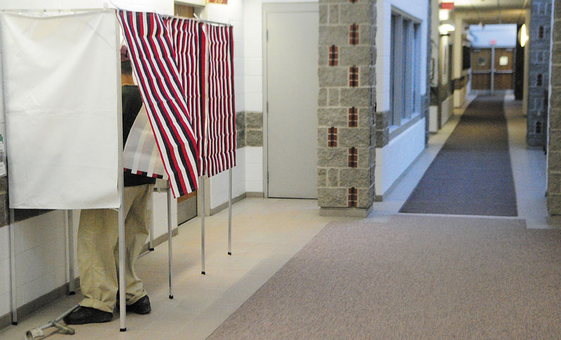 Mike Bradley fills in his absentee ballot in a voting booth in a hallway near the city clerk's office recently in Augusta City Center.