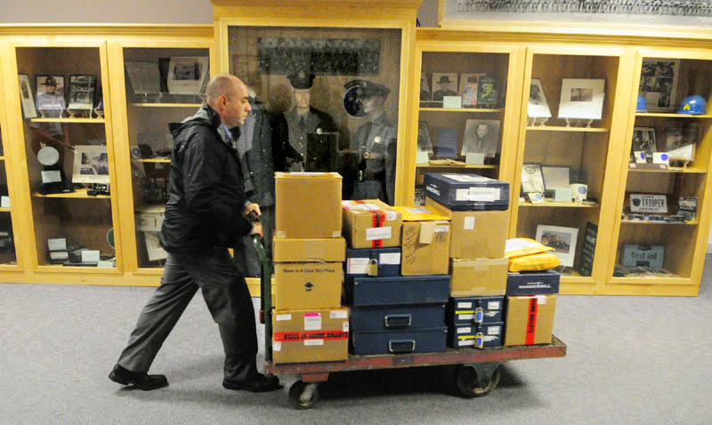 Maine State Police Sgt. Mike Zabursky rolls a cart of ballot boxes past display cases towards Florian Hall on Tuesday afternoon at the Department of Public Safety headquarters on Commerce Drive in Augusta. Troopers were bringing ballots boxes there for recounts scheduled to begin Wednesday morning.