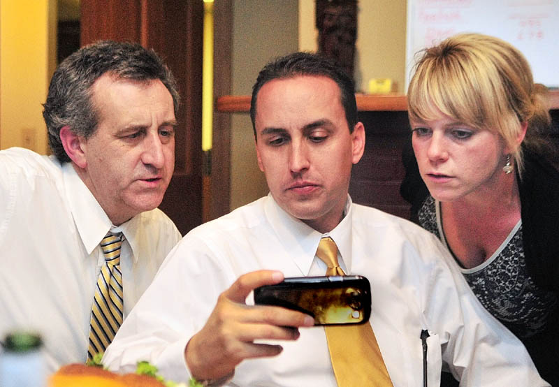 Staff photo by Joe Phelan Ron Bourget, district attorney candidate Darrick Banda, and Avian Moores look at results on Banda's phone on Tuesday night in Bourget's Augusta law office.