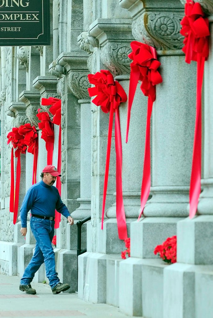 A person walks in the The Olde Federal Building on Wednesday in downtown Augusta. The flowers and red ribbons on the large ornate building at the corner of Water and Winthrop streets were from last weekend's tree lighting events when it was Santa's castle.