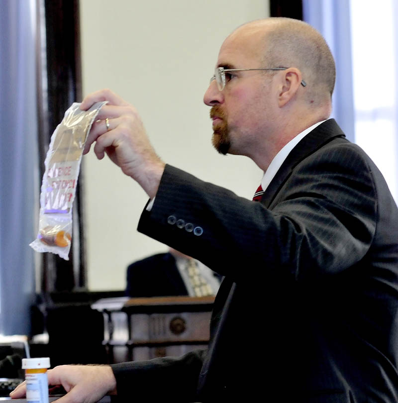 Assistant Attorney General Don Macomber holds a bag filled with prescription drugs in his opening statement against defendant Robert Nelson, on trial in the death of Everett Cameron in Skowhegan Superior Court, on Monday.
