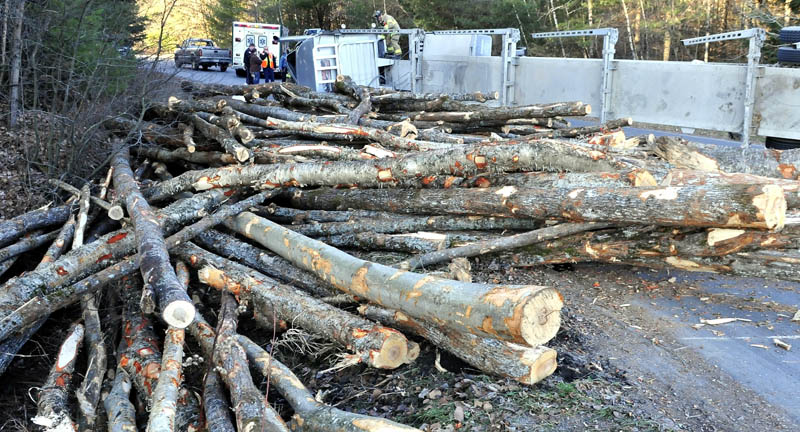 Skowhegan firefighters inspect the cab of an overturned truck that rolled over near Sappi Fine Papers, on U.S. Route 201 in Skowhegan, on Monday, and spilled a load of logs.