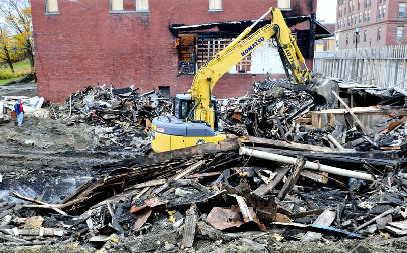 Property owner Bob Hagopian, left, watches on Thursday as an equipment operator cleans up the burned remains of a former antique store that burned last March on Main Street in Madison. Hagopian plans to rebuild at the site next spring. "Everyone is excited that I am cleaning this up," he said.
