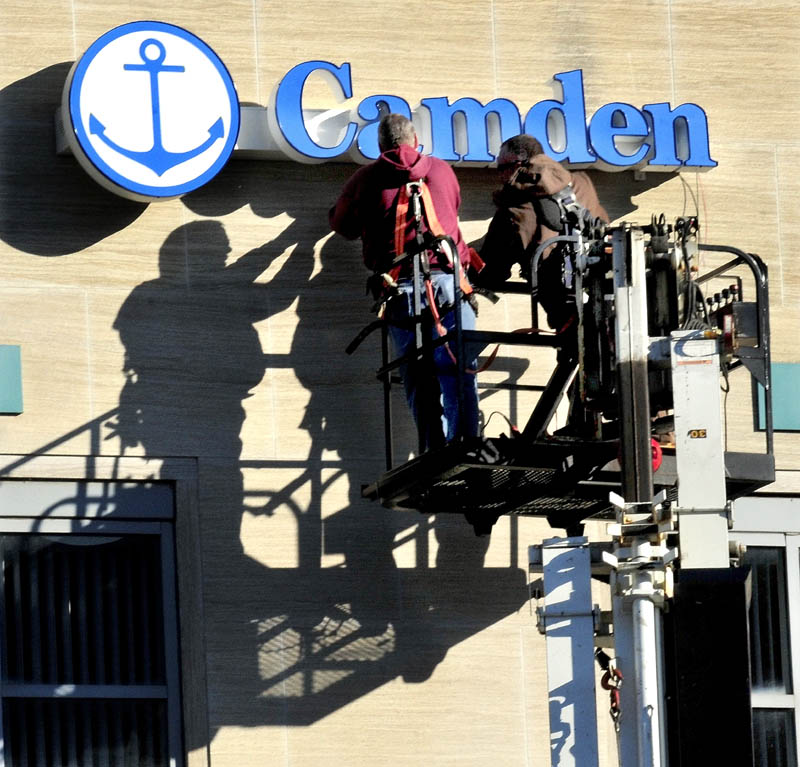 Workers with NeoKraft Signs company install the Camden National Bank sign on the former Bank of America branch on Main Street in Waterville on Tuesday. Bank of America sold its branches in Maine north of Lewiston earlier this year.