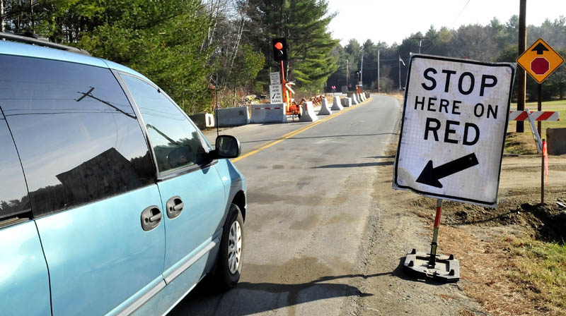 A motorist stops and waits for the signal to proceed along a portion of the Whittier Road in Farmington on Wednesday. The road has been closed due to erosion near the Sandy River, but this week officials reopened one lane to traffic.